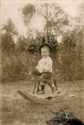 [Portrait de garçonnet sur un cheval à bascule-jouet] : photographie N. et B. collée sur album, Dim. 114 x 167 cm. 