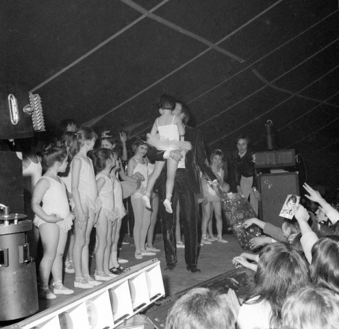 Claude FRANCOIS en fin de concert, tenant dans ses bras les petites danseuses du Club des jeunes, 2 avril 1968, négatif noir et blanc.