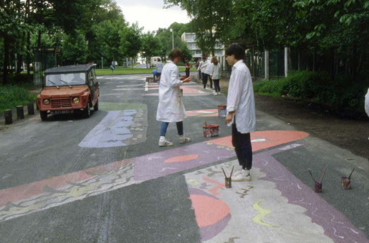 COURCOURONNES, parc de la Garenne. - Peinture au sol de la rue Emile Biort par Vincent GUIRO et les élèves du CES Paul Fort, vues de la réalisation : une boîte de diapositives (7 mai 1984). 