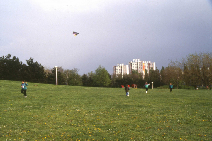 EVRY, parc Henri Fabre. - Cerf volants devant le parc aux Lièvres, paquerettes dans la pelouse, cimetière vu à travers les arbres, et divers : une boîte de diapositives (avril 1991).
