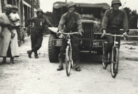 Libération, arrivée des Américains, passage d'un véhicule de transport précédé par deux soldats en bicyclette, 1944 