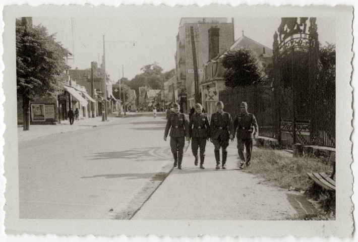 DRAVEIL.- Occupation de la ville par l'armée allemande : des soldats allemands marchant dans une rue du centre-ville, devant la grille de la cité Paris-Jardin.