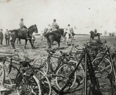 Rassemblement et revue des troupes, faisceaux de fusils et bicyclettes : photographie noir et blanc.