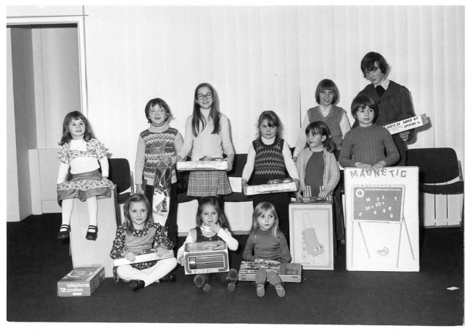 EVRY.- Le Noël des enfants du personnel du syndicat communautaire de la ville d'EVRY : un groupe d'enfants photographiés avec leur cadeau, [1975], N et B. 
